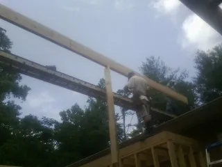 Carpenter setting a ridge beam over a new addition frame — Ice Dam Removal by Roofing Brothers in Eaton Center