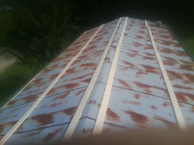 Rusted metal roof panels with new wood purlins before replacement — Storm Damage Roof Repair in Eaton Center by Roofing Brothers