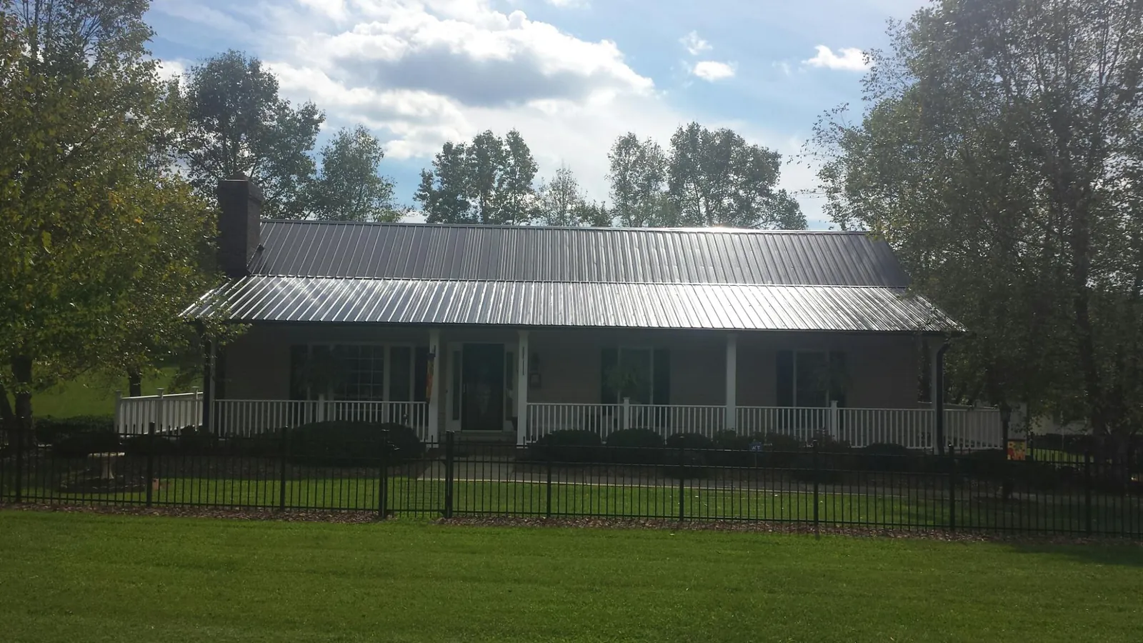 Gray metal roof on a brick ranch with a full width front porch — Gutter Guard Installation work by our crew in Eaton Center
