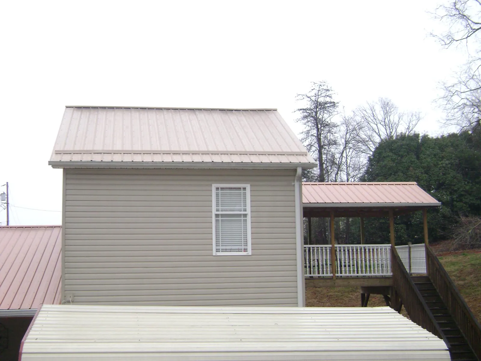 Tan metal roofs on a two story addition and attached porch, from a Roof Replacement job in Eaton Center