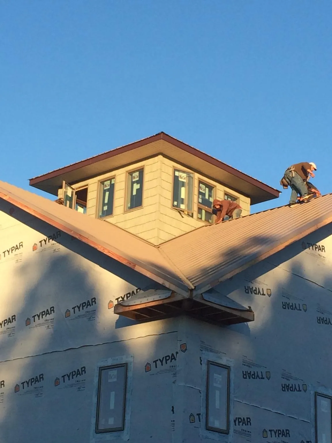 Roofers working around a rooftop cupola on a new metal roof at sunset — Roof Waterproofing in Eaton Center by Roofing Brothers